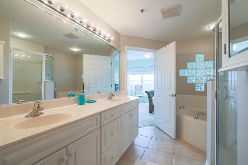a bathroom with two sinks and a tub and a mirror at 3 Bedroom 2 Bath Oceanwalk Condo With Estuary Views in New Smyrna Beach