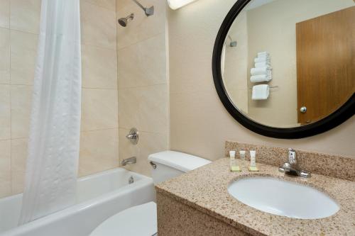 a bathroom with a sink and a tub and a mirror at Super 8 by Wyndham Waycross GA in Waycross