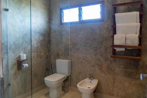 a bathroom with a toilet and a glass shower at Visiwa Beach Resort in Watamu