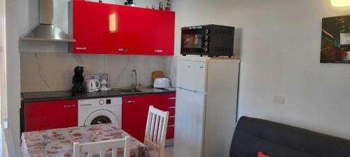 a small kitchen with red cabinets and a white refrigerator at Vivienda Ida - Costa Del Silencio Tenerife in Costa Del Silencio