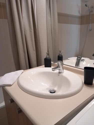 La salle de bains est pourvue d'un lavabo blanc et d'un miroir. dans l'établissement Cocon reposant à 10min du centre de Bordeaux, à Lormont