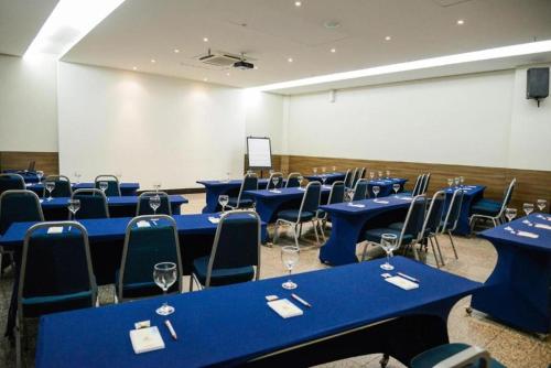 a room with blue tables and chairs and a white screen at Taiwan Hotel in Ribeirão Preto