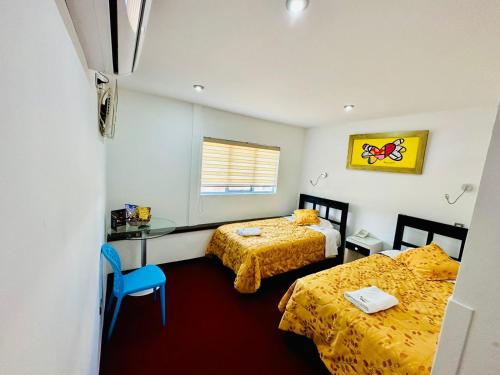 Cette chambre comprend deux lits, un bureau et une fenêtre. dans l'établissement Le Prince Arica, à Arica