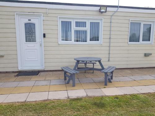 a picnic table and two benches in front of a house at Summer Days in Camber