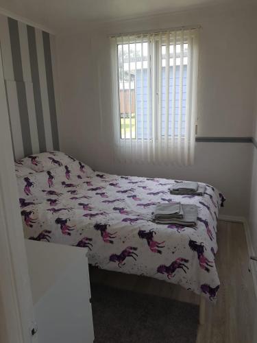 a bedroom with a bed with a comforter and a window at Summer Days in Camber