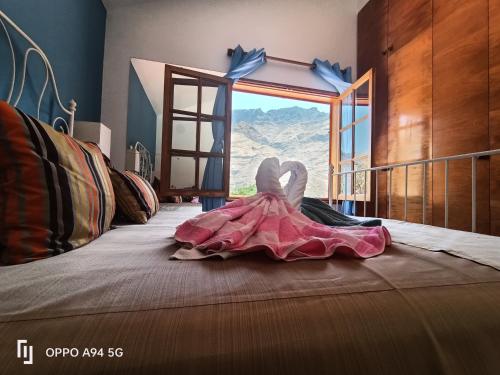 un vestido sentado en la parte superior de una cama con ventana en Chalet Juana La Concha Valle de Agaete, en San Pedro