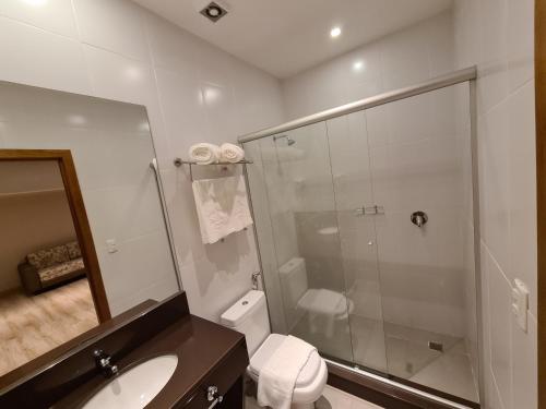 een badkamer met een douche, een toilet en een wastafel bij Sky Borges Hotel Alpenhaus - Gramado in Gramado