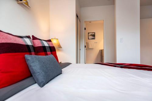 a bedroom with a white bed with red pillows at The Shred Shack - Stylish Revelstoke Condo in Revelstoke