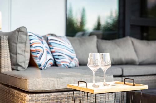 two wine glasses on a table in front of a couch at The Shred Shack - Stylish Revelstoke Condo in Revelstoke