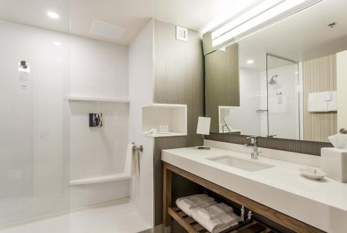 a white bathroom with a sink and a mirror at Courtyard by Marriott Montreal West Island/Baie D’Urfe in Baie-dʼUrfé