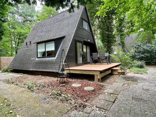 una pequeña casa negra con porche y banco en Gezellige Caban in de natuur, en Lanaken