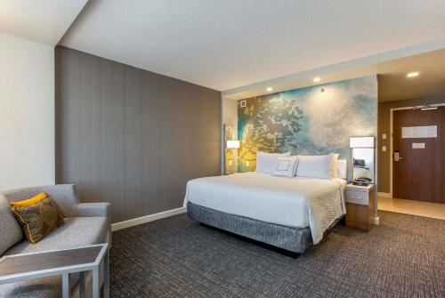 a hotel room with a bed and a couch at Courtyard by Marriott Montreal West Island/Baie D’Urfe in Baie-dʼUrfé