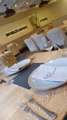 a wooden table with plates and forks and wine glasses at Hotel Zum Anker-THULLs Restaurant in Neumagen-Dhron
