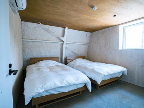 two beds in a small room with a window at FOX&CRANE Cabin - Vacation STAY 97723v in Teshikaga
