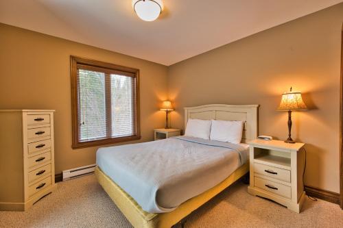 a bedroom with a bed with two night stands and a window at Rabaska by Rendez-Vous Mont-Tremblant in Mont-Tremblant