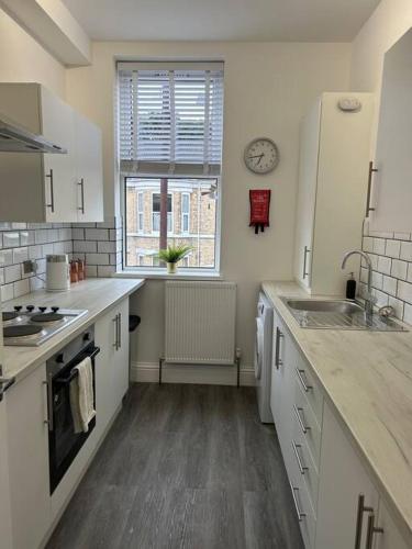 a kitchen with white cabinets and a sink and a window at Stylish 1 bed apartment in Hull