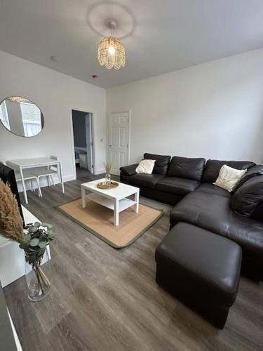 een woonkamer met een zwarte bank en een tafel bij Stylish 1 bed apartment in Hull