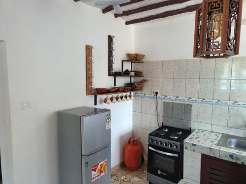 a kitchen with a refrigerator and a stove at Kimbi's Place in Ukunda