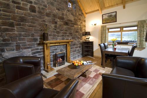 a living room with a stone wall with a fireplace at Clan Cottages in Oban
