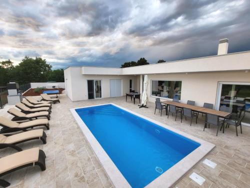 a house with a swimming pool and chairs and a table at Villa Mare e Monti with heated pool in Umag