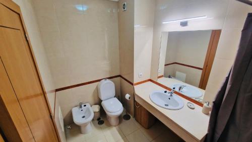 een badkamer met een wastafel, een toilet en een spiegel bij Sofiamarholidays- Casa levante in Portimão