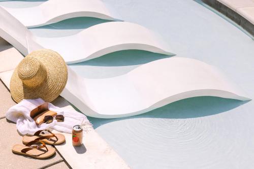 une paire de sandales et un chapeau à côté d'une piscine dans l'établissement Sonder at Village 21, à Nashville