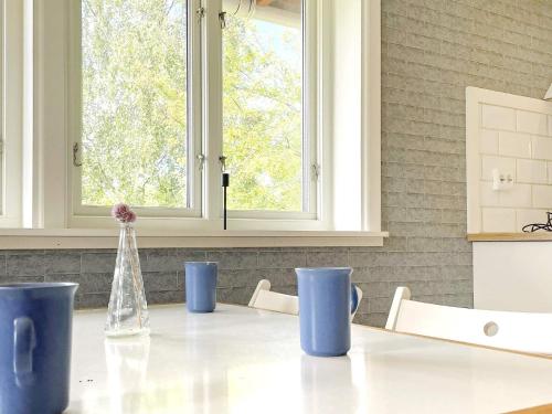 Holiday home UDDEVALLA XL في Sundsandvik: طاولة في مطبخ مع أكواب زرقاء ونافذة