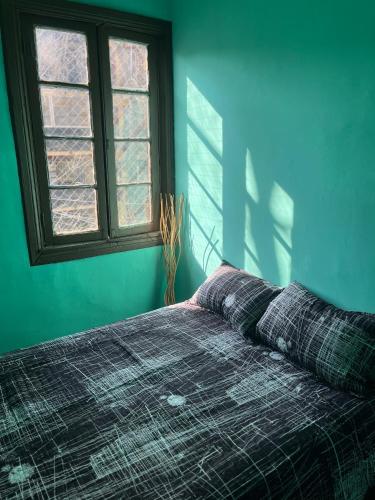 1 dormitorio con 1 cama con manta y ventana en Hostal Colors Bellavista, en Santiago