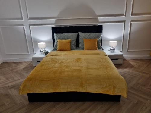 een slaapkamer met een groot geel bed met 2 lampen bij SKYAPART in Kłodzko