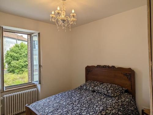 a bedroom with a bed and a chandelier and a window at Gite de Marcella in Saint-Dizier-Leyrenne