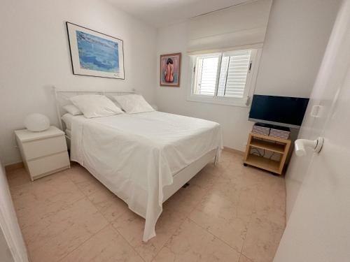 um quarto branco com uma cama e uma televisão em Sitges Aiguadolç playa em Sitges