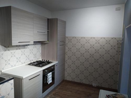 uma cozinha com armários brancos e um forno com placa de fogão em Venanzio! em Pianello Del Lario