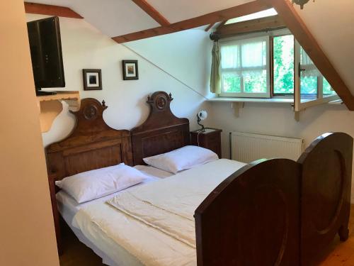 Schlafzimmer mit einem Bett mit einem Kopfteil aus Holz und einem TV in der Unterkunft etno kuća Đeram in Mokrin