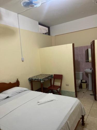1 dormitorio con cama, mesa y baño en Alojamiento Grau en Tarapoto