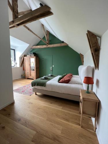 een slaapkamer met een bed en een groene muur bij Le Logis de la Lettre in Tinténiac