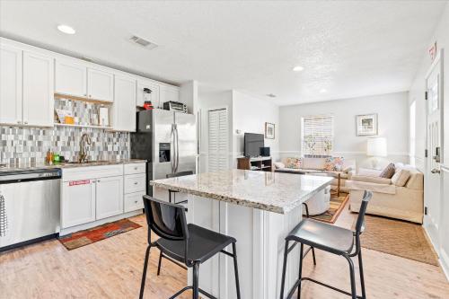 a kitchen and living room with a counter and chairs at Cute Downtown Cottage with Large Yard and BBQ plus Smart TVs in Saint Augustine