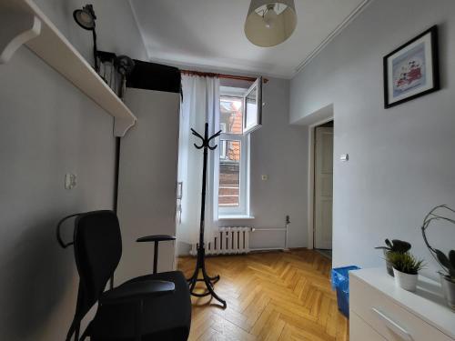 a living room with a black chair and a staircase at Zabytkowa Kamienica in Gdańsk