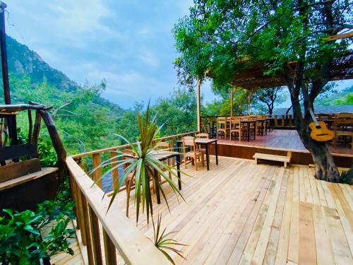 a wooden deck with tables and chairs and a guitar at Reflections Camp in Faralya