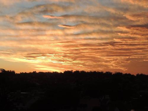 a cloudy sky at sunset with trees in the foreground at Punta Mogotes,hermosa vista al mar y al atardecer in Mar del Plata