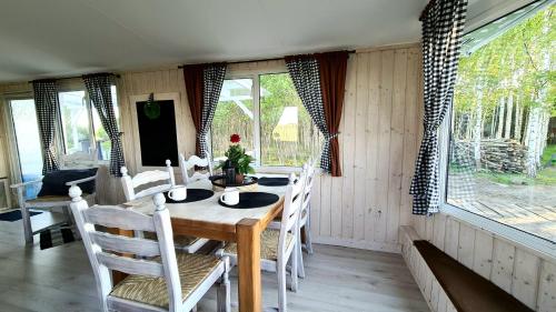 a dining room with a table and chairs and windows at Domki Mierzeja 