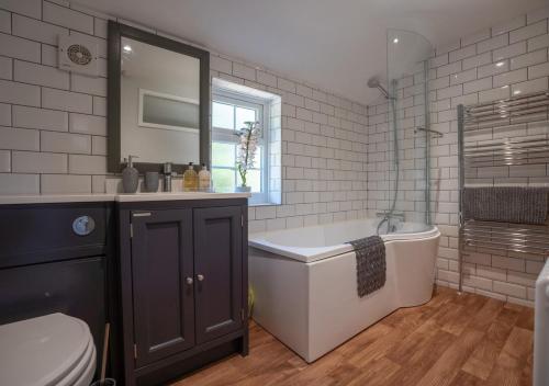 a bathroom with a tub and a sink and a toilet at Flint Cottage in Debenham