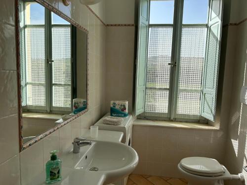 ein Badezimmer mit einem Waschbecken, einem WC und einem Spiegel in der Unterkunft La Dispensa in Montalto delle Marche