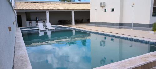 a swimming pool with two chairs and a building at Confort Lencois Preguicas in Barreirinhas
