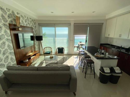 a living room with a couch and a kitchen at Departamento en renta en The One Mazatlan in Mazatlán