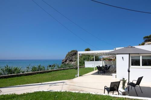 a patio with an umbrella and chairs and the ocean at Casa Sabbia 10m from the beach in Pelekas