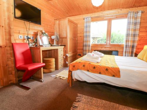 a bedroom with a bed and a red chair at Heathcliff Lodge in Northallerton