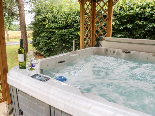 a hot tub with a bottle of wine and a glass at Heathcliff Lodge in Northallerton