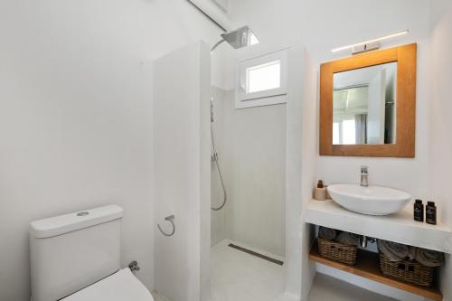 a white bathroom with a sink and a mirror at Casa Sabbia 10m from the beach in Pelekas