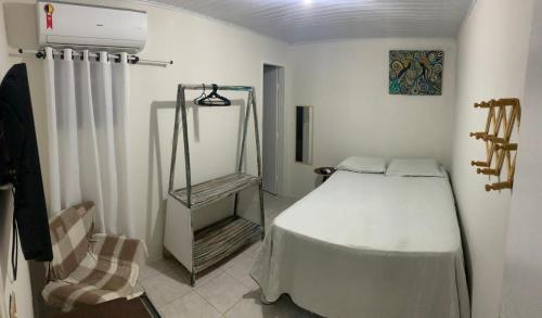 ein Schlafzimmer mit einem weißen Bett und einem Stuhl in der Unterkunft Pousada Aconchego in Aracaju
