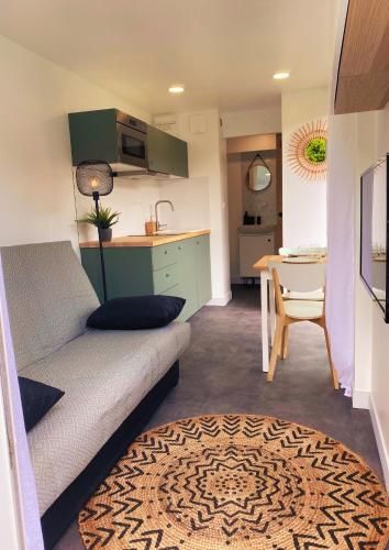 a living room with a couch and a kitchen with a table at Studio container au look bohème in Poisat